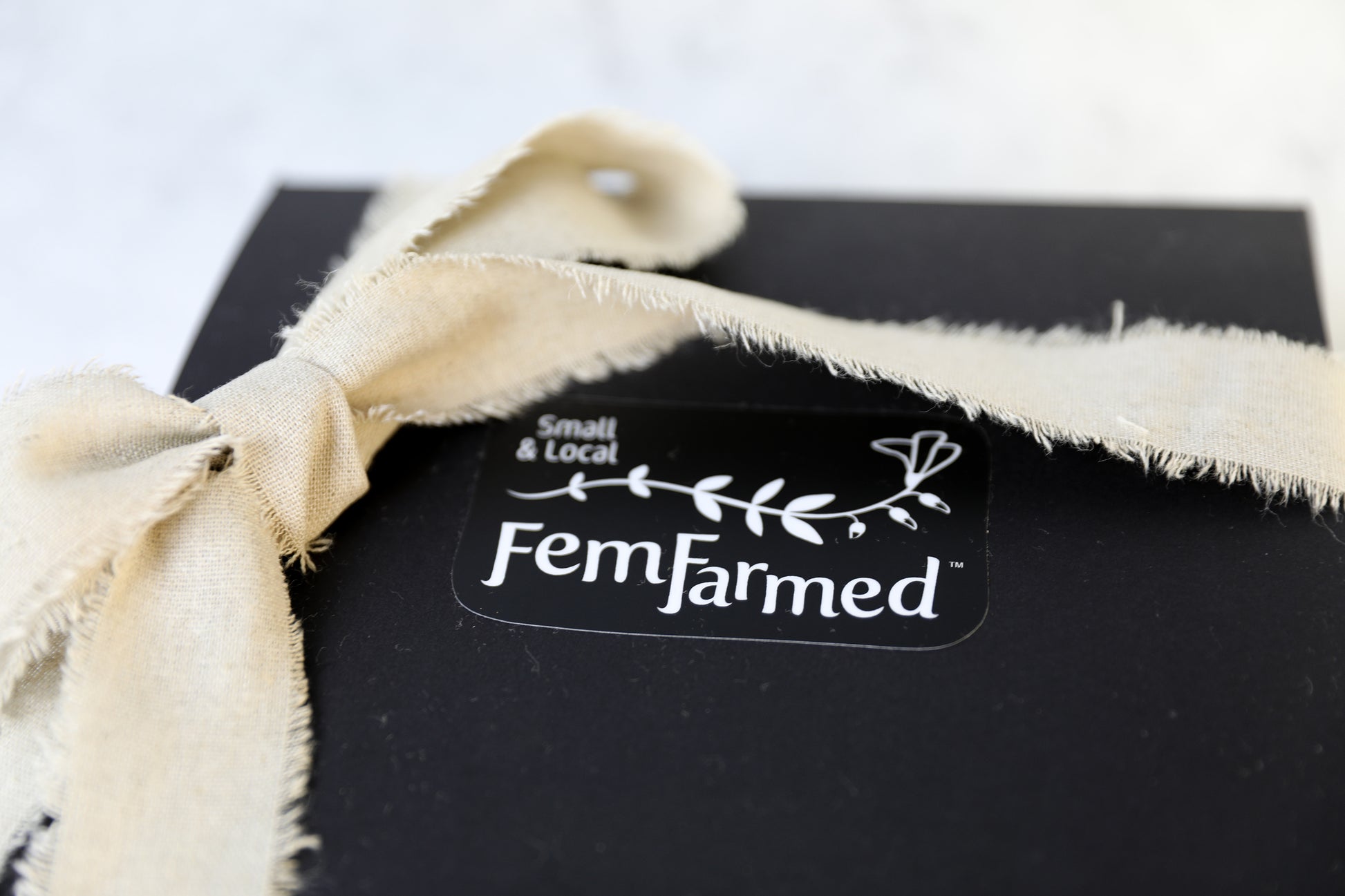 Outside of black FemFarmed Gift Box with cream linen ribbon